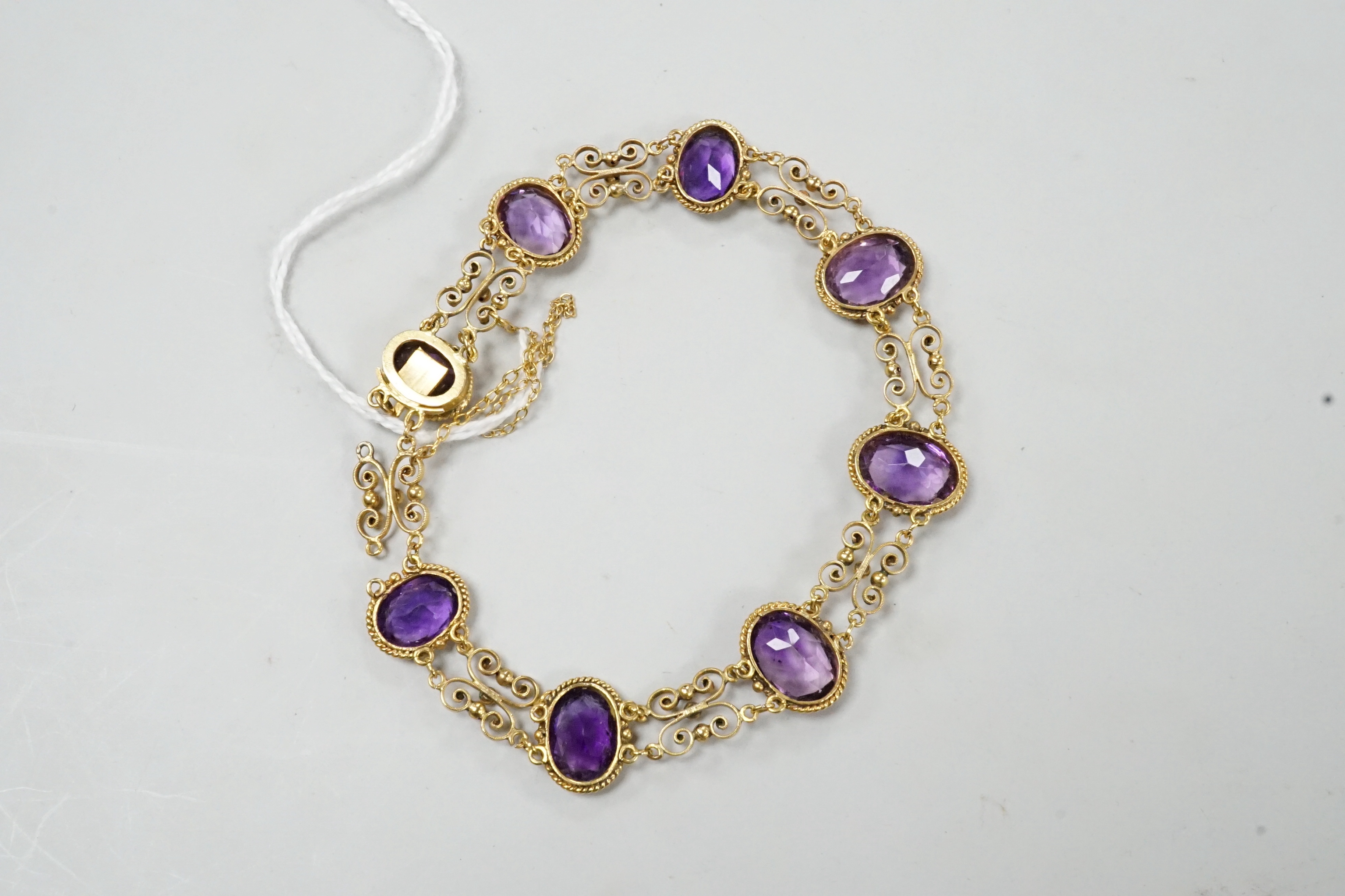 A late Victorian yellow metal and eight stone oval cut amethyst set fancy link bracelet, 18cm, gross weight 9.6 grams.